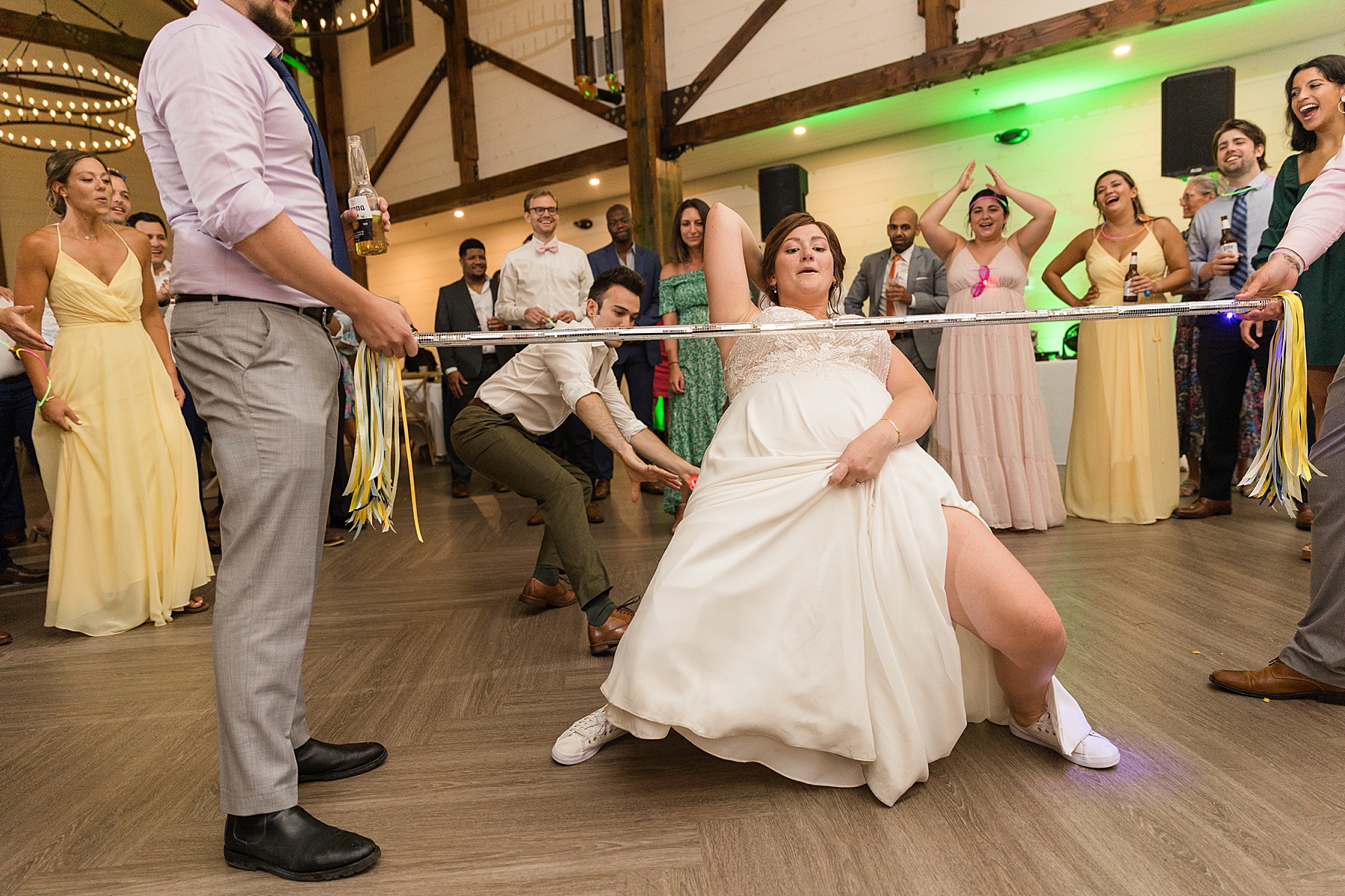 candid wedding guests dancing limbo bride