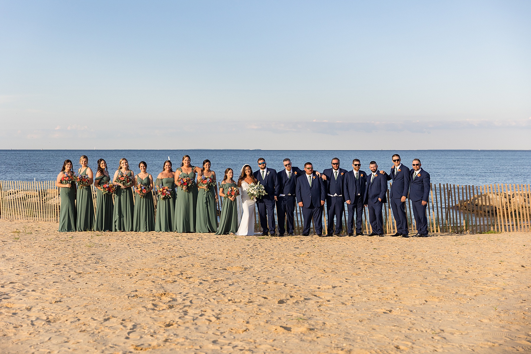 couple with full wedding party green and navy beachy