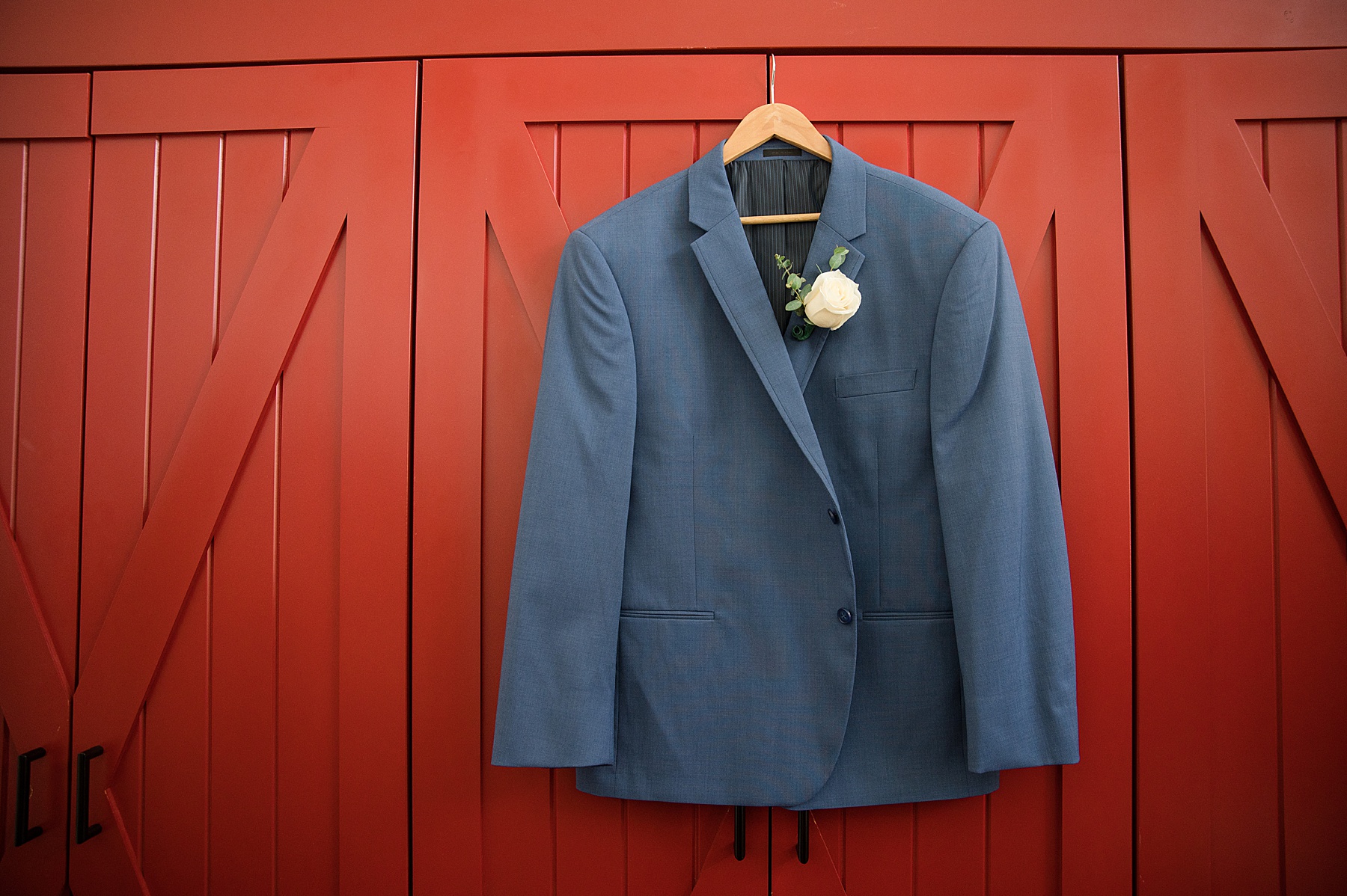 groom's jacket hanging on barn door