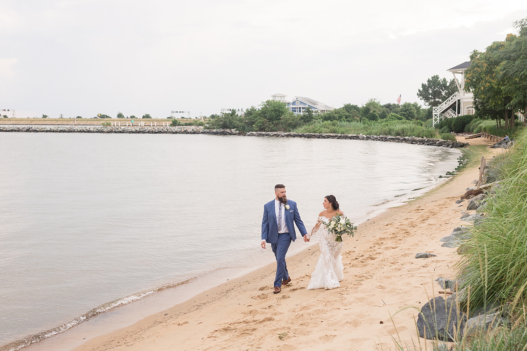 bride and groom walk along shoreline