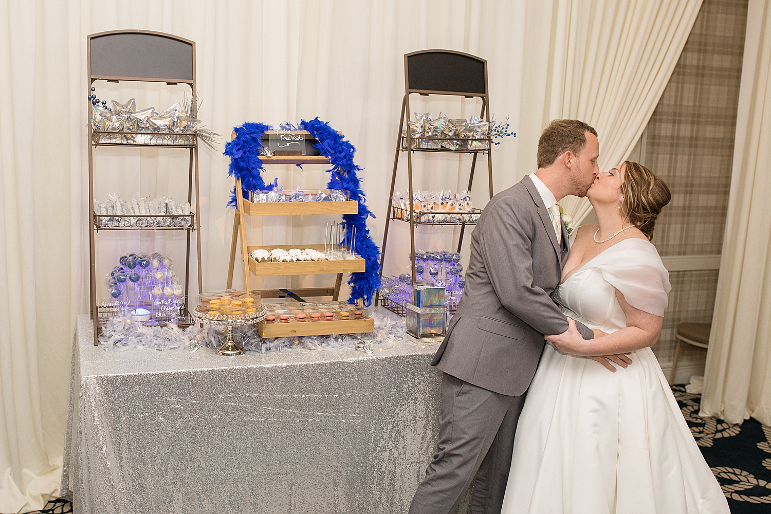 bride and groom kiss beside dessert table