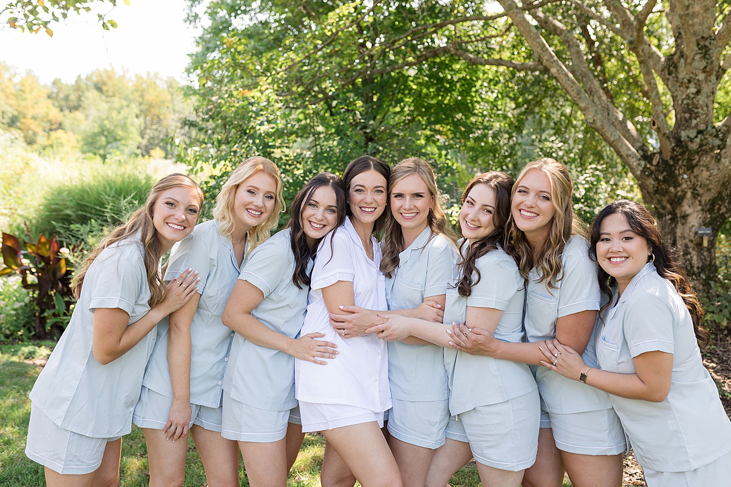 bride and bridesmaids in getting ready outfits hug