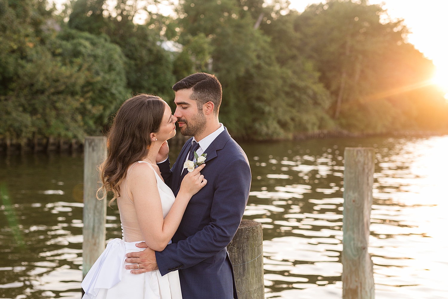 bride and groom on pier at sunset kiss