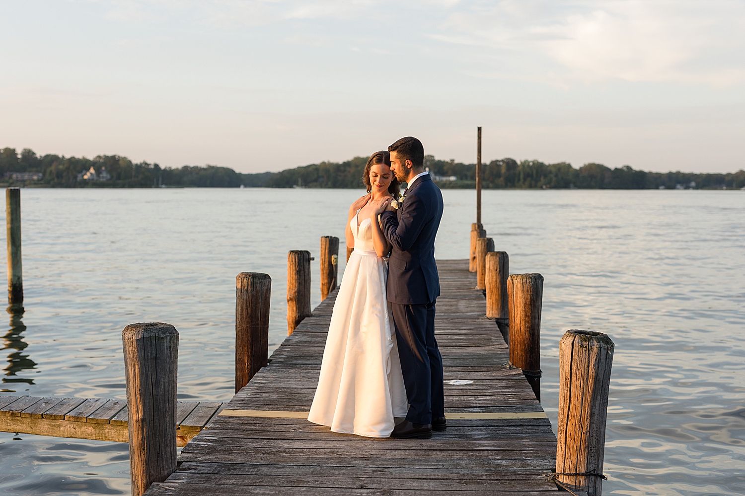 bride and groom on pier at sunset