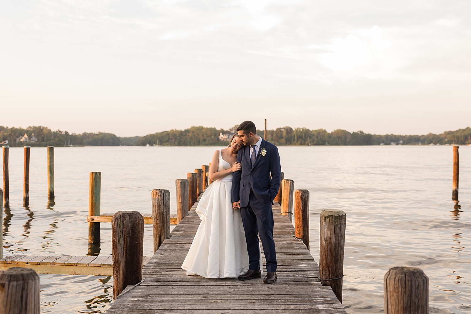 bride and groom on pier at sunset