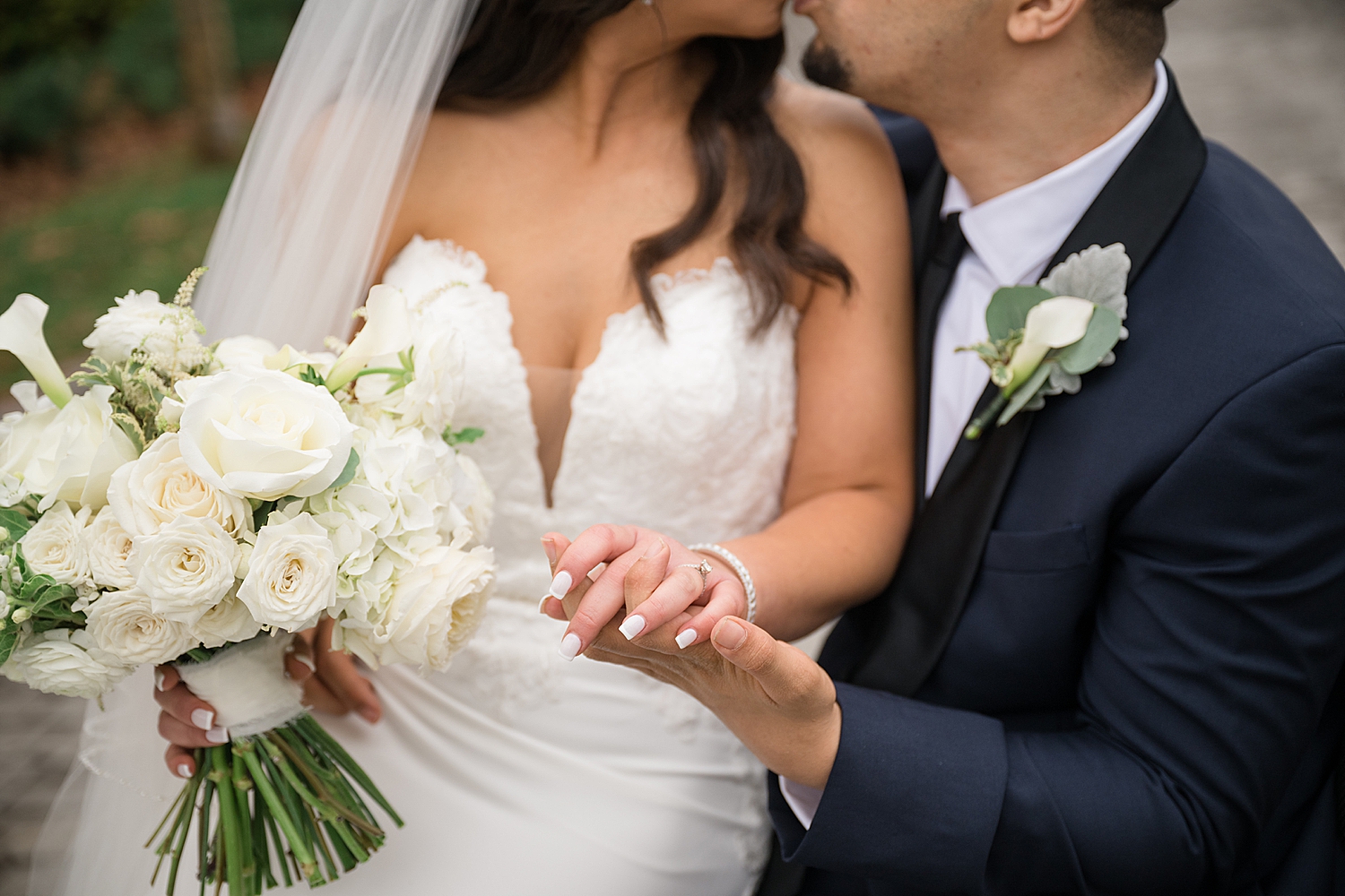 bride and groom holding hands as they kiss