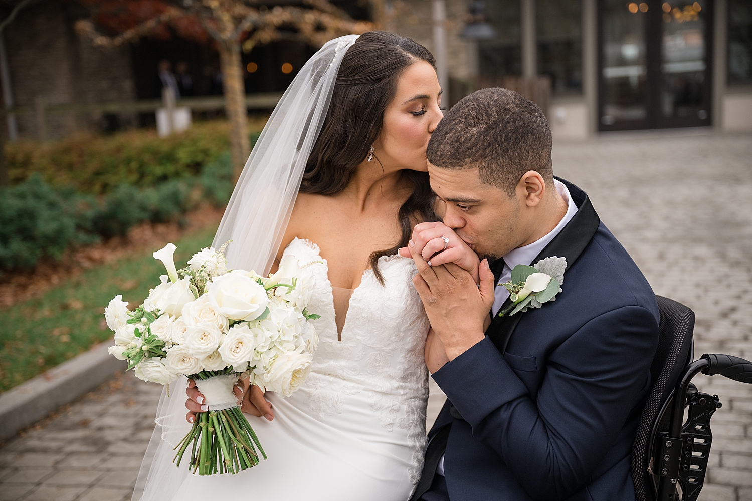 couple portrait groom kisses bride's hand