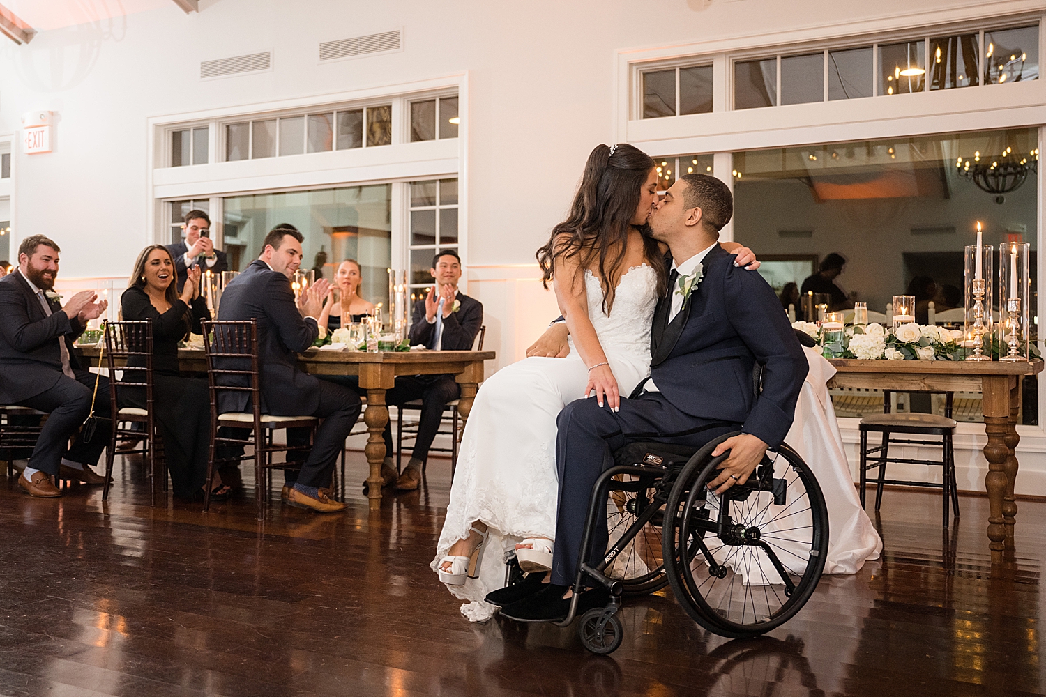 bride and groom kiss after reception entrance bride sitting in groom's lap in wheelchair