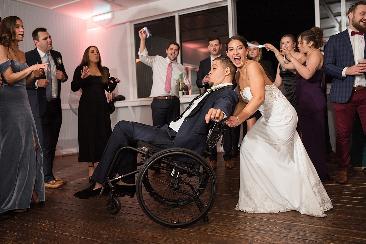 guests dancing candid bride tilts groom's wheelchair