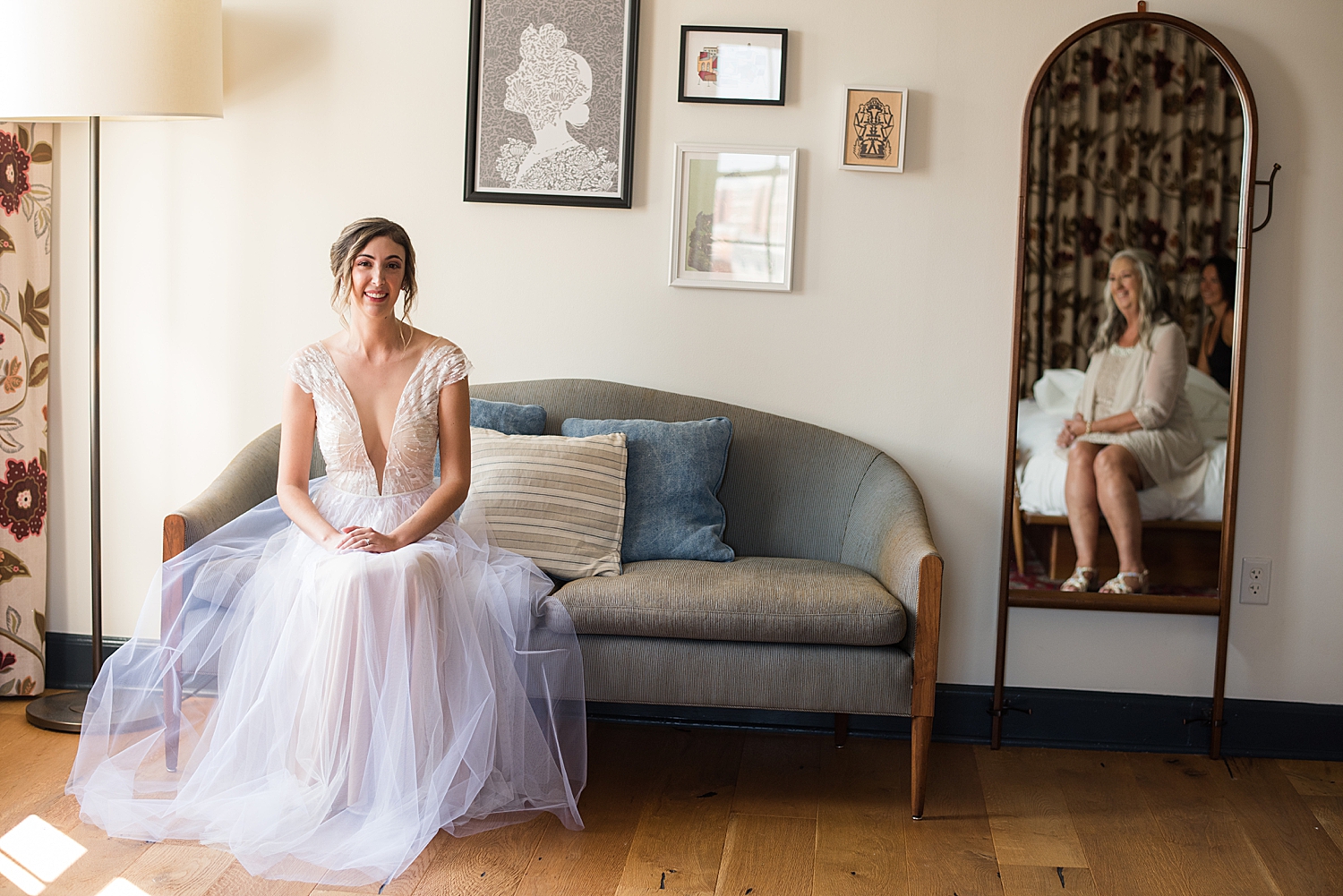 bride sitting on sofa smiling at mom in mirror