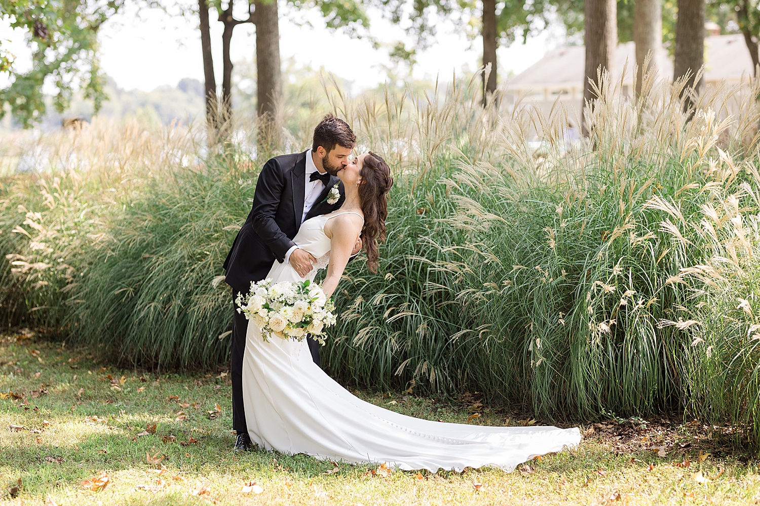 bride and groom dip kiss green field