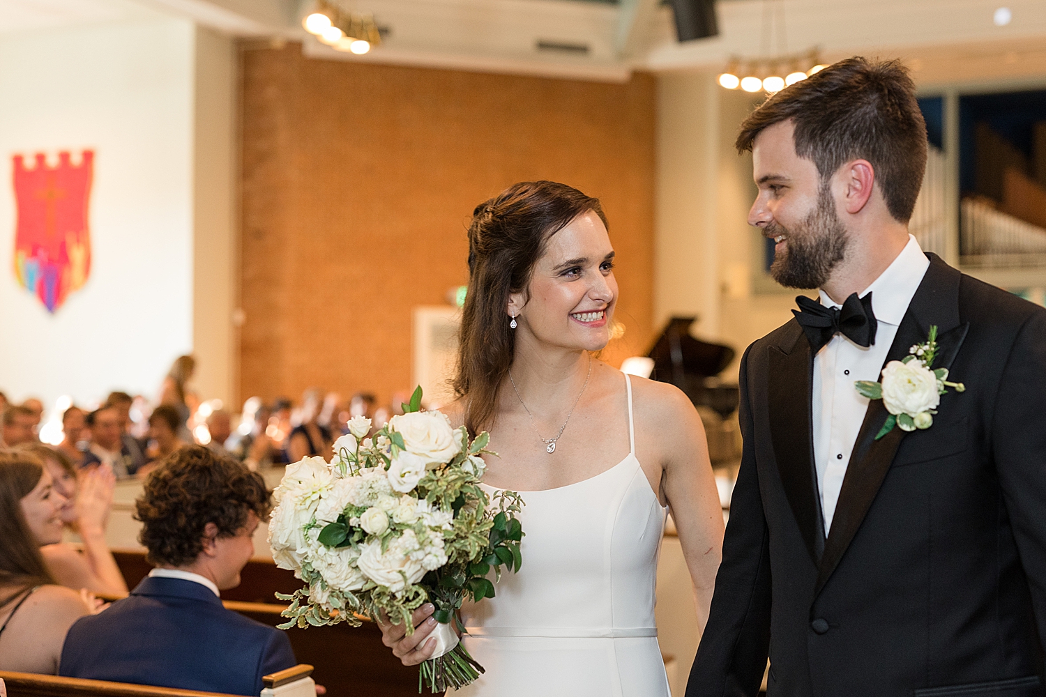 bride and groom smile as they exit church ceremony