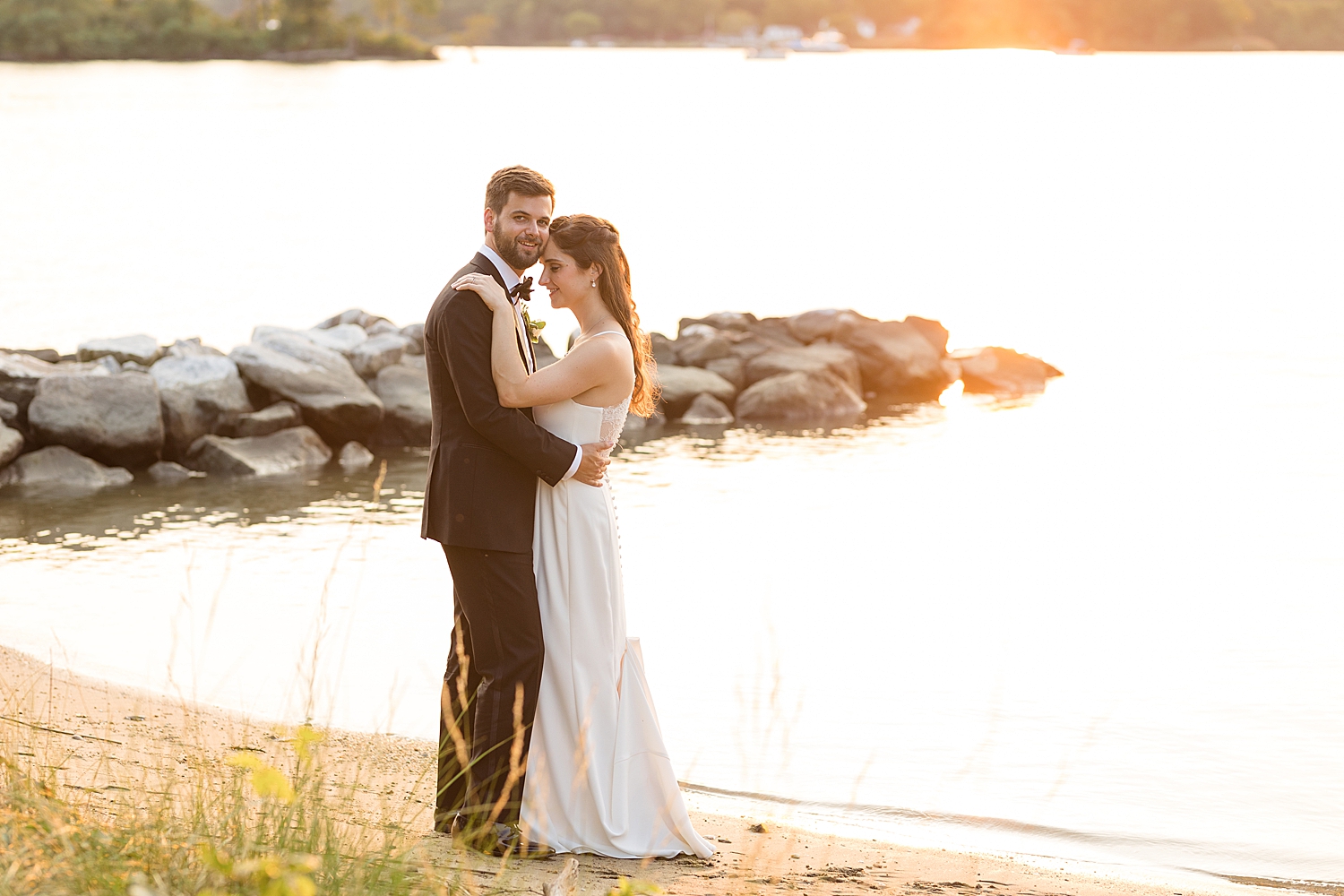 bride and groom embrace on beach at sunset