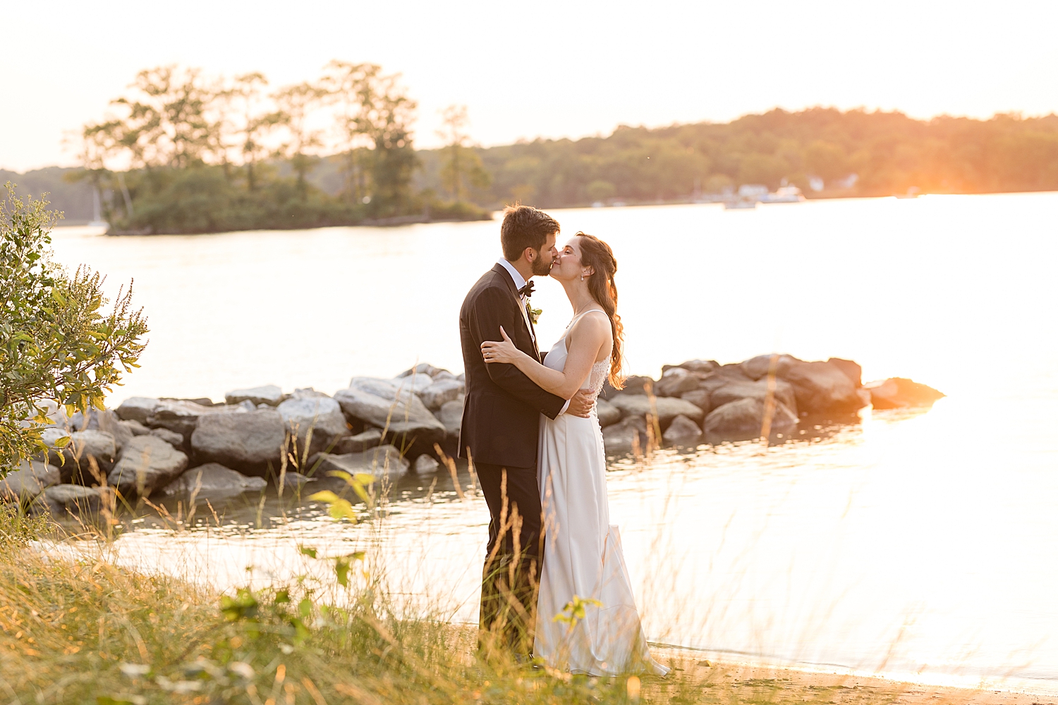 bride and groom embrace on beach at sunset