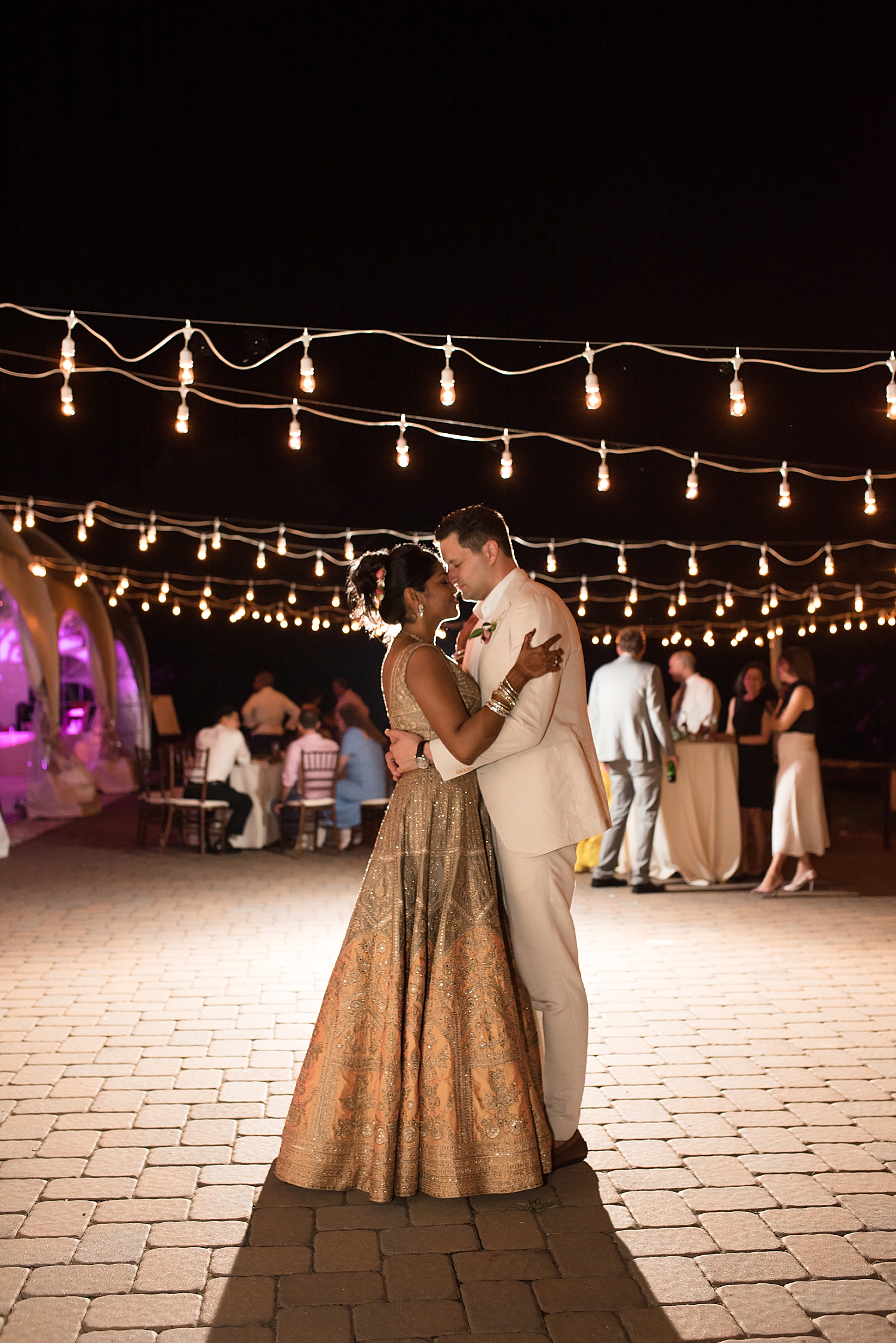 bride and groom kiss under bistro lights