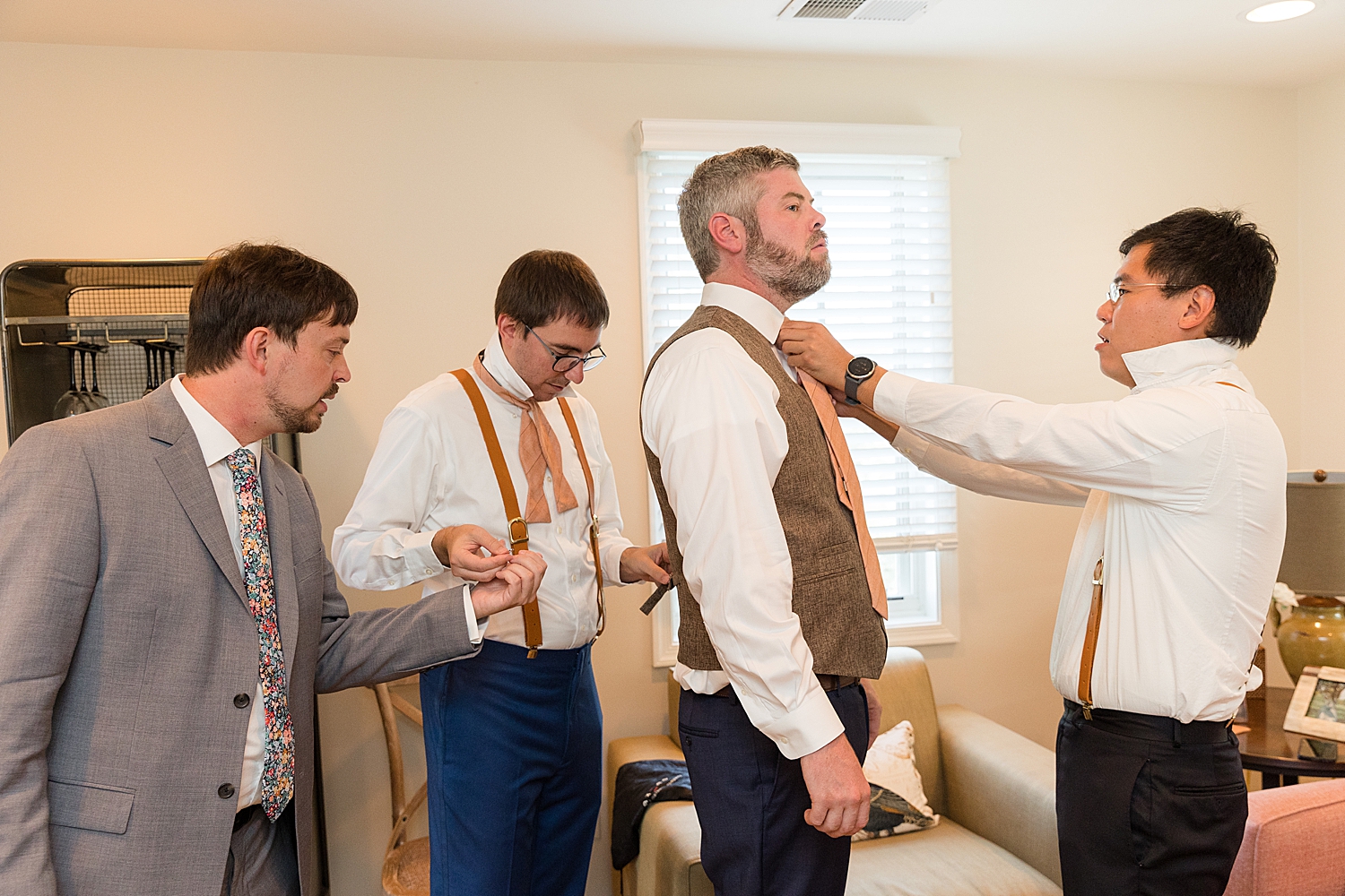 groom getting ready with groomsmen fixing tie