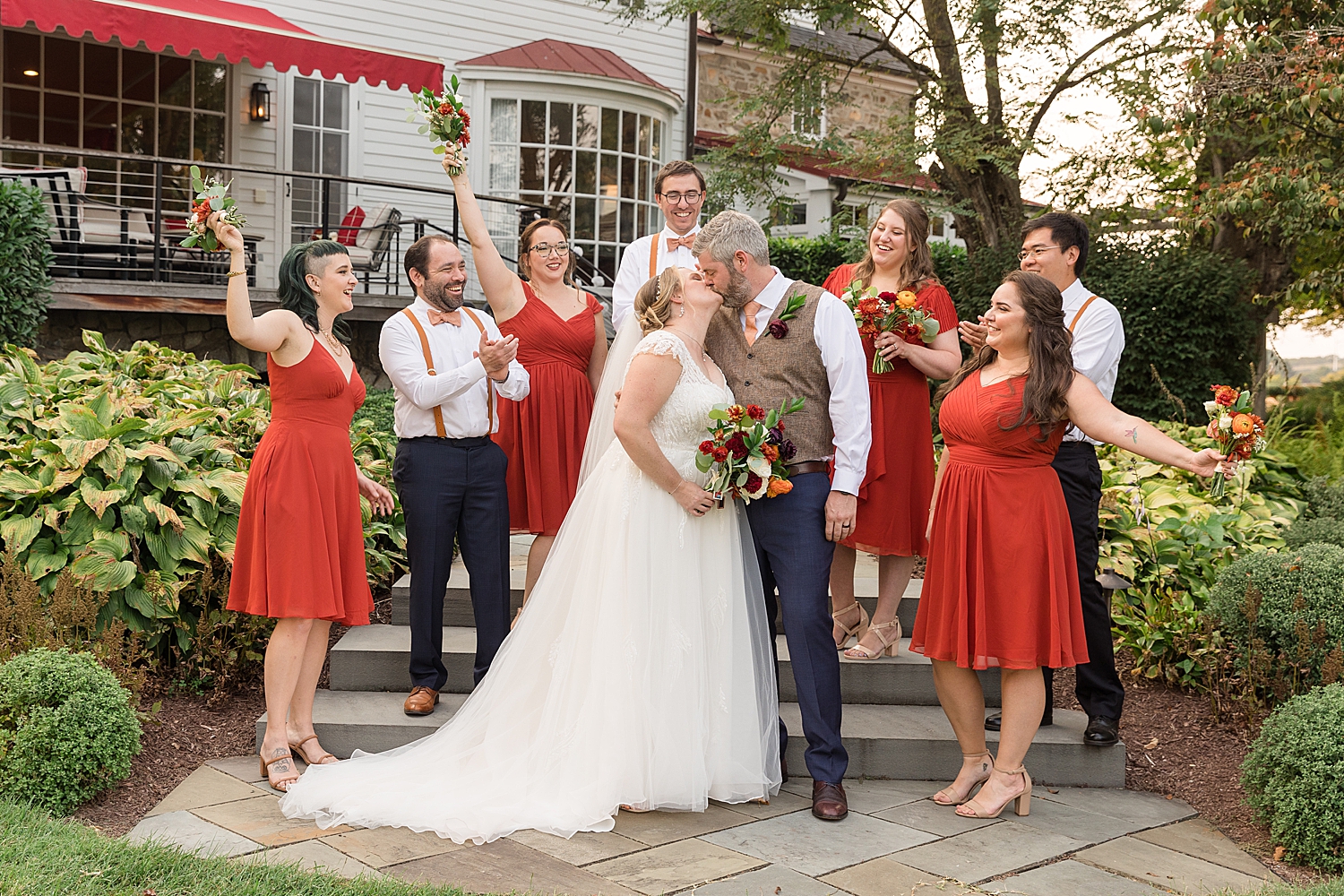 bride and groom kissing while wedding party cheers