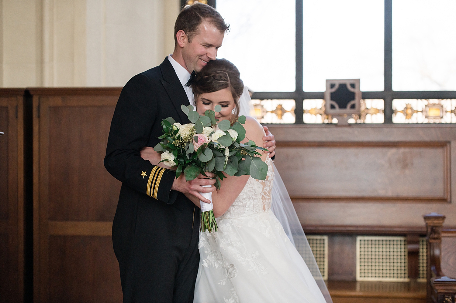 bride and groom hug in usna chapel loft