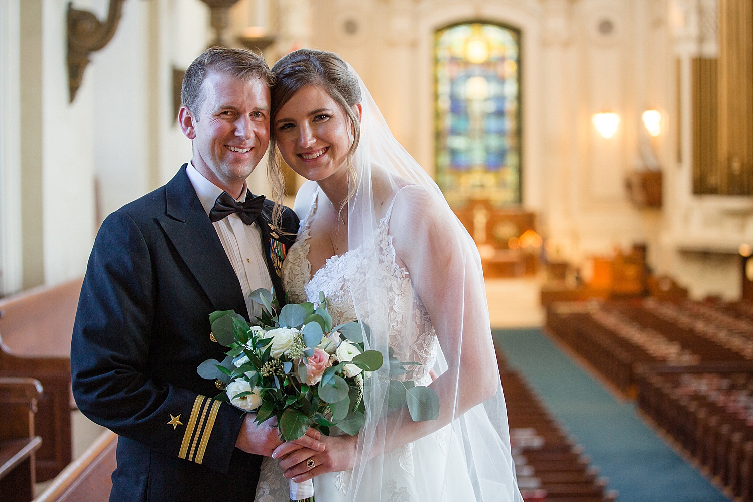 bride and groom smile at camera in usna chapel loft