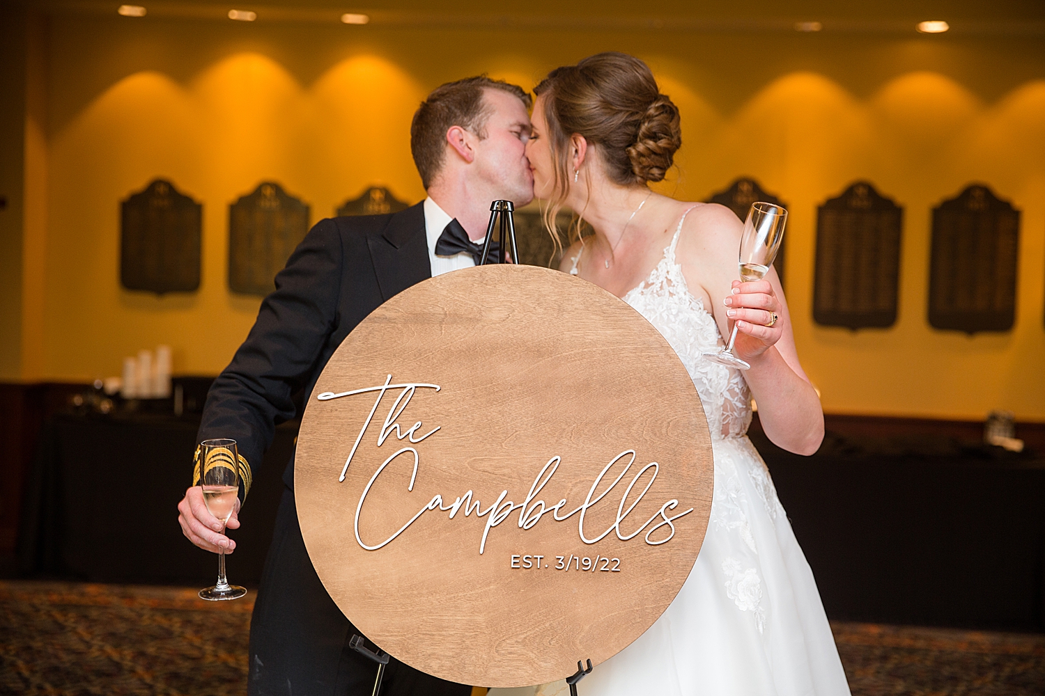 bride and groom kiss behind sign with new last name