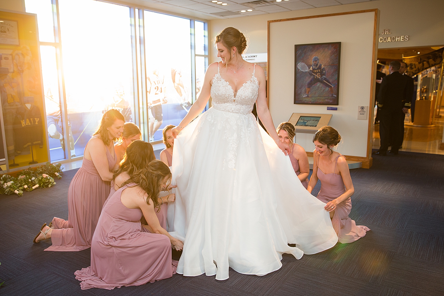 bridesmaids helping bride with gown as sun sets