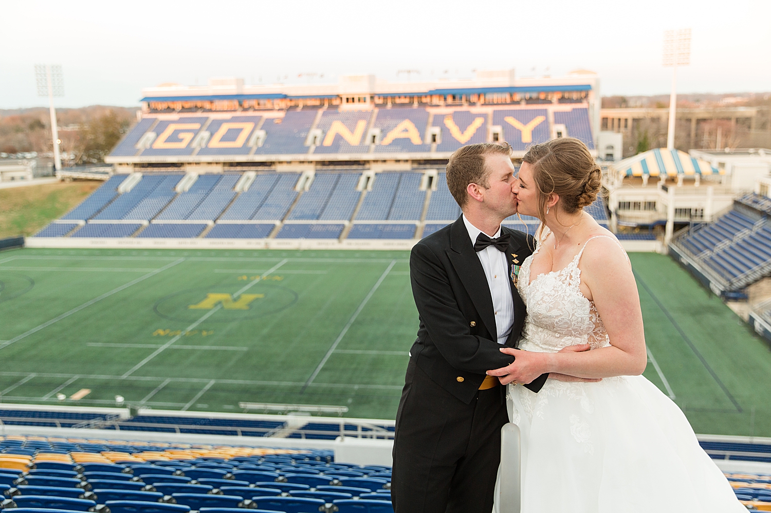 bride and groom kissing in stands at navy stadium