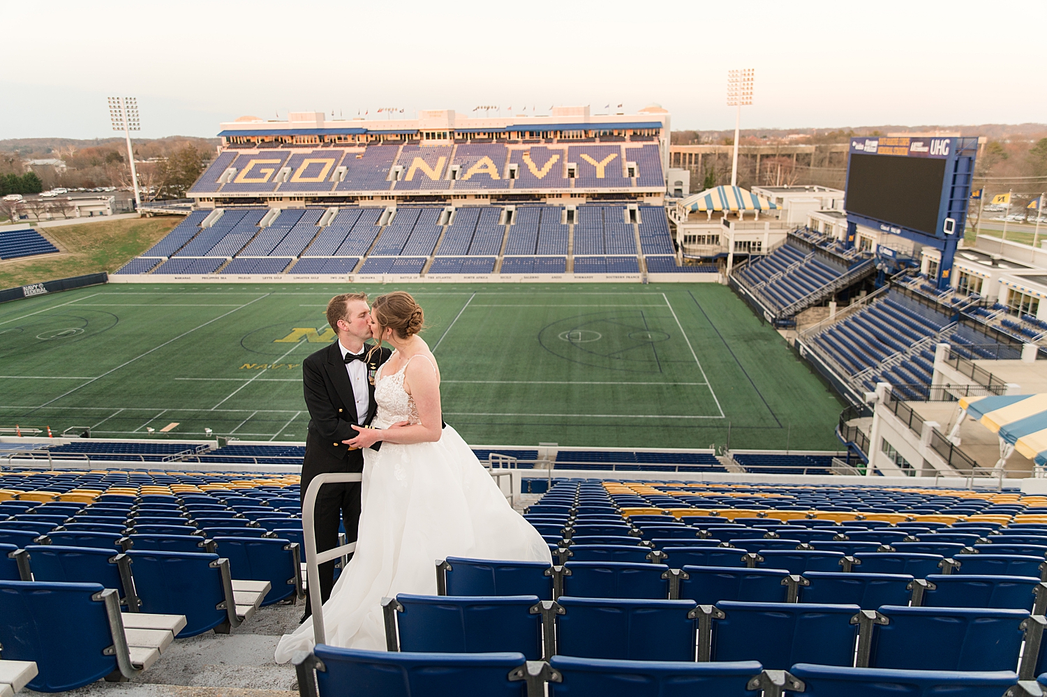 bride and groom kissing in stands at navy stadium