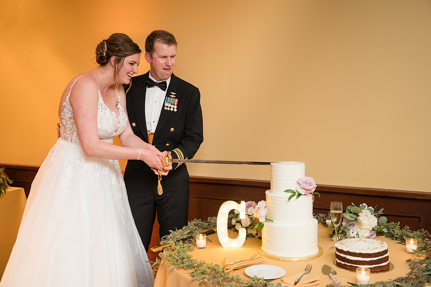 bride and groom cut wedding cake with sword at usna stadium