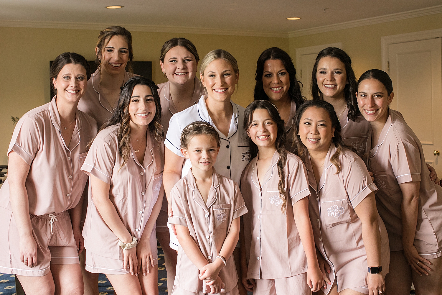 bride, bridesmaids, and flower girls smile at the camera in getting ready outfits