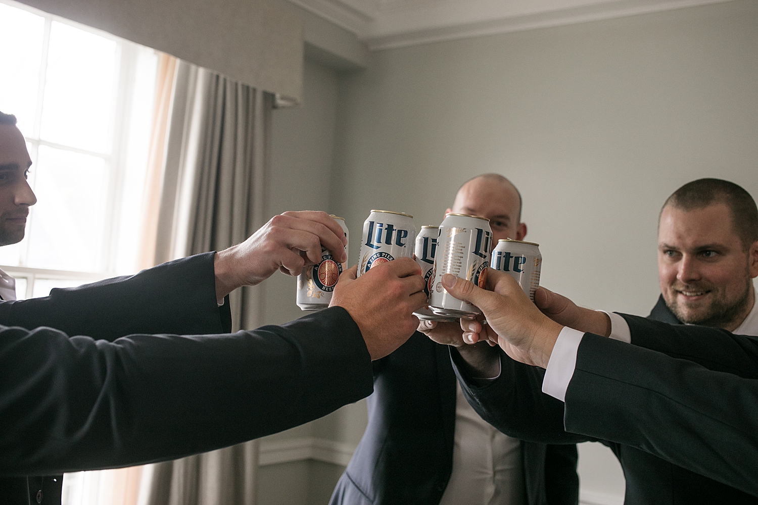 groom toasts with beers with his groomsmen