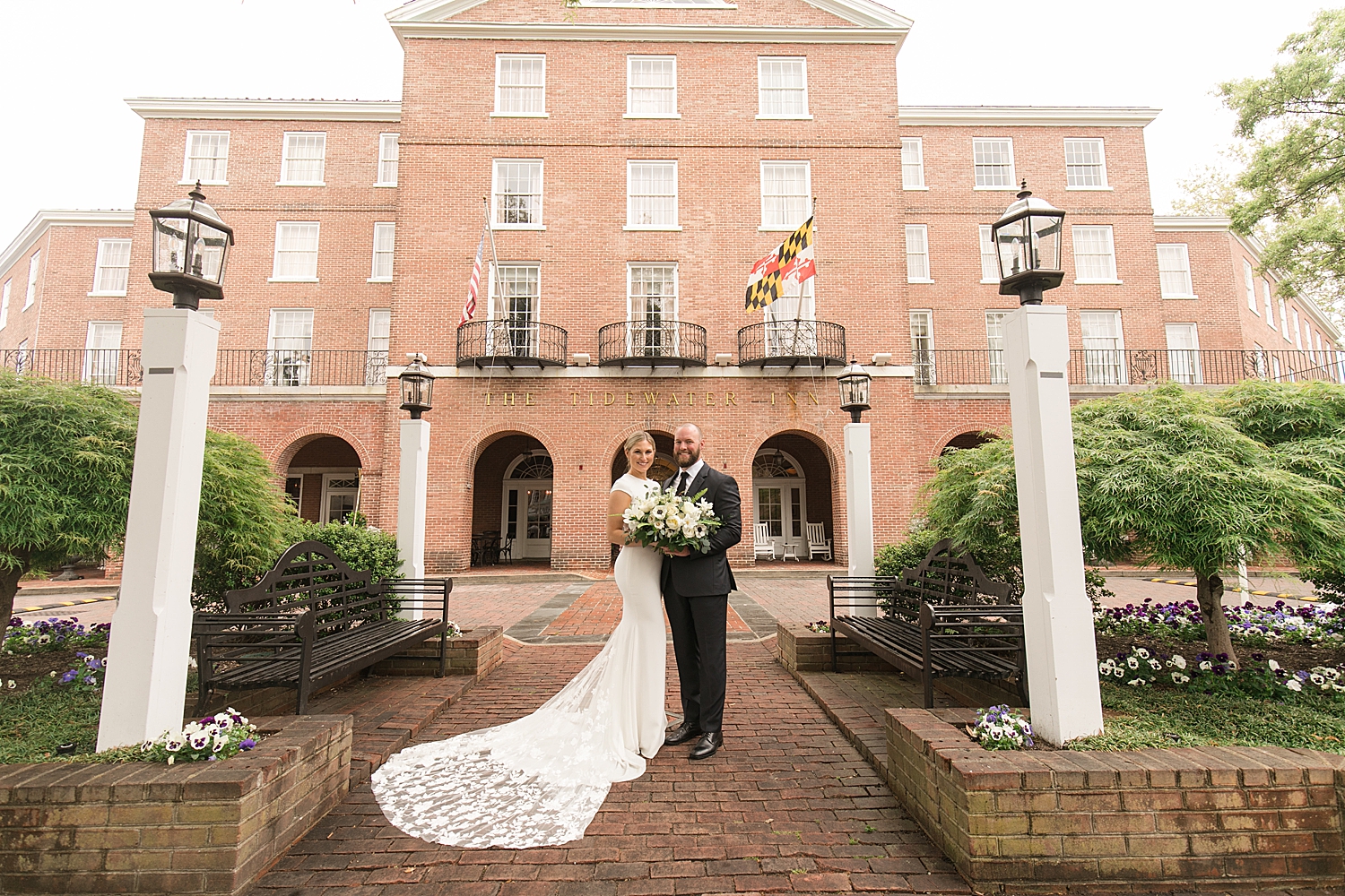 bride and groom kiss in front of tidewater inn brick