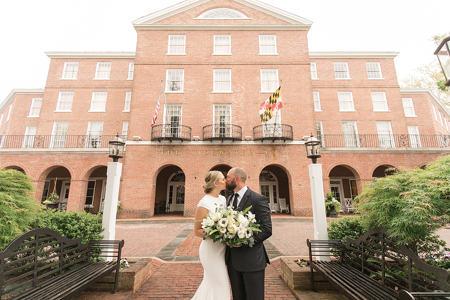 bride and groom kiss in front of tidewater inn brick