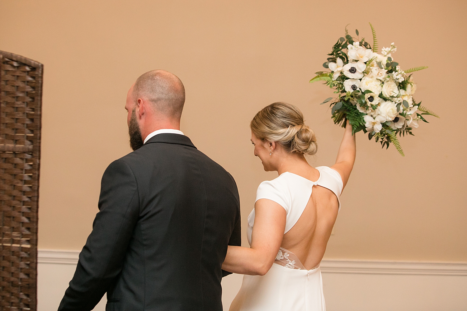 bride and groom recess from ceremony, bride celebrates with bouquet in air