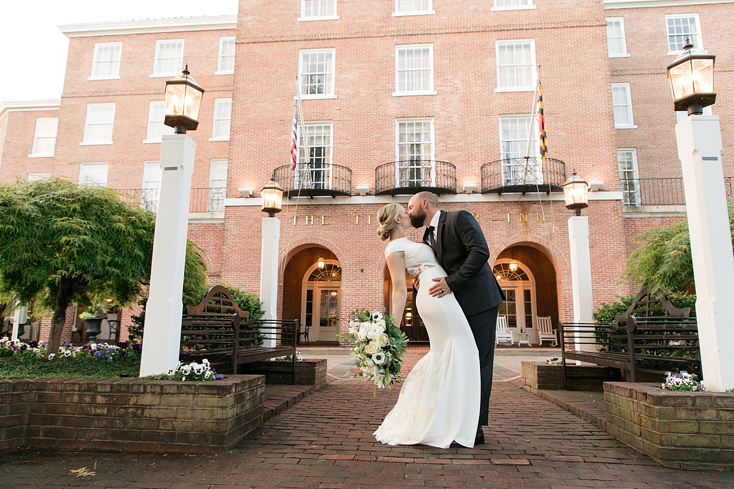 bride and groom kiss in front of tidewater inn brick arches