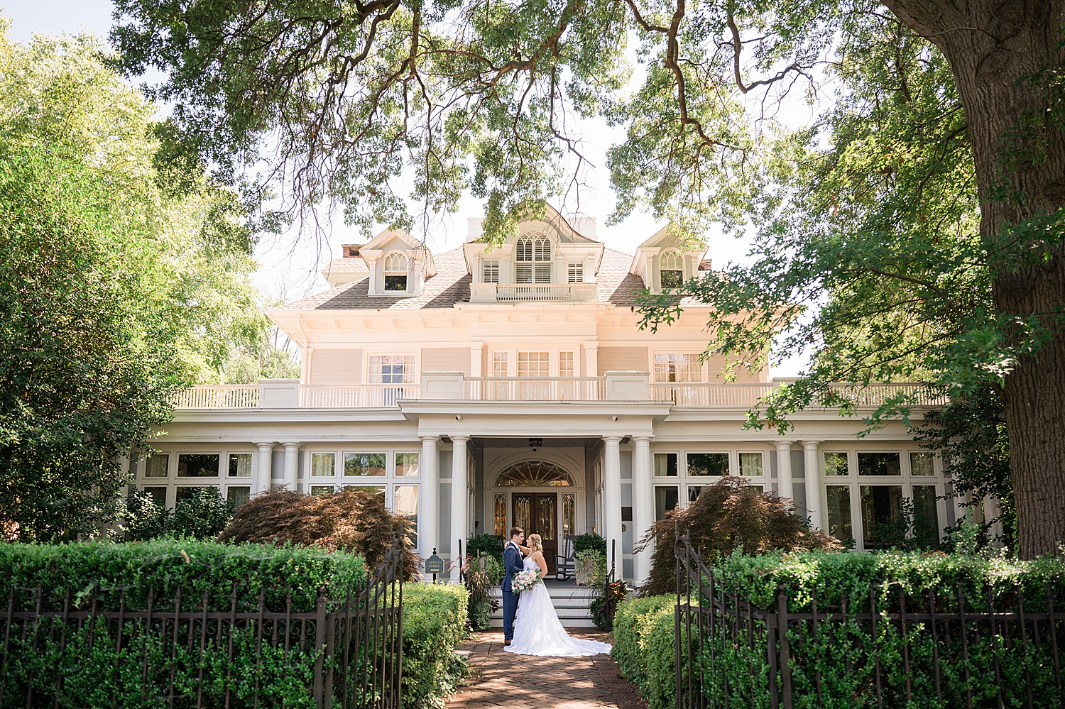 bride and groom kiss in front of house