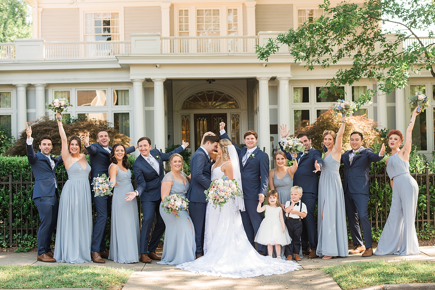 wedding party cheers while bride and groom kiss