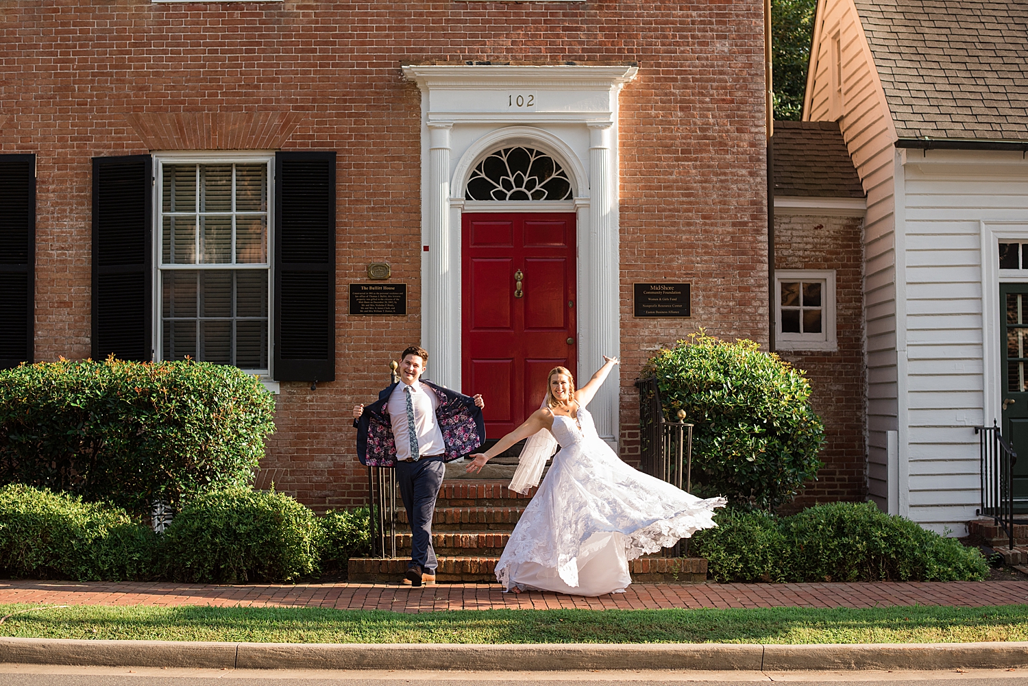 bride and groom celebrate silly in front of brick building