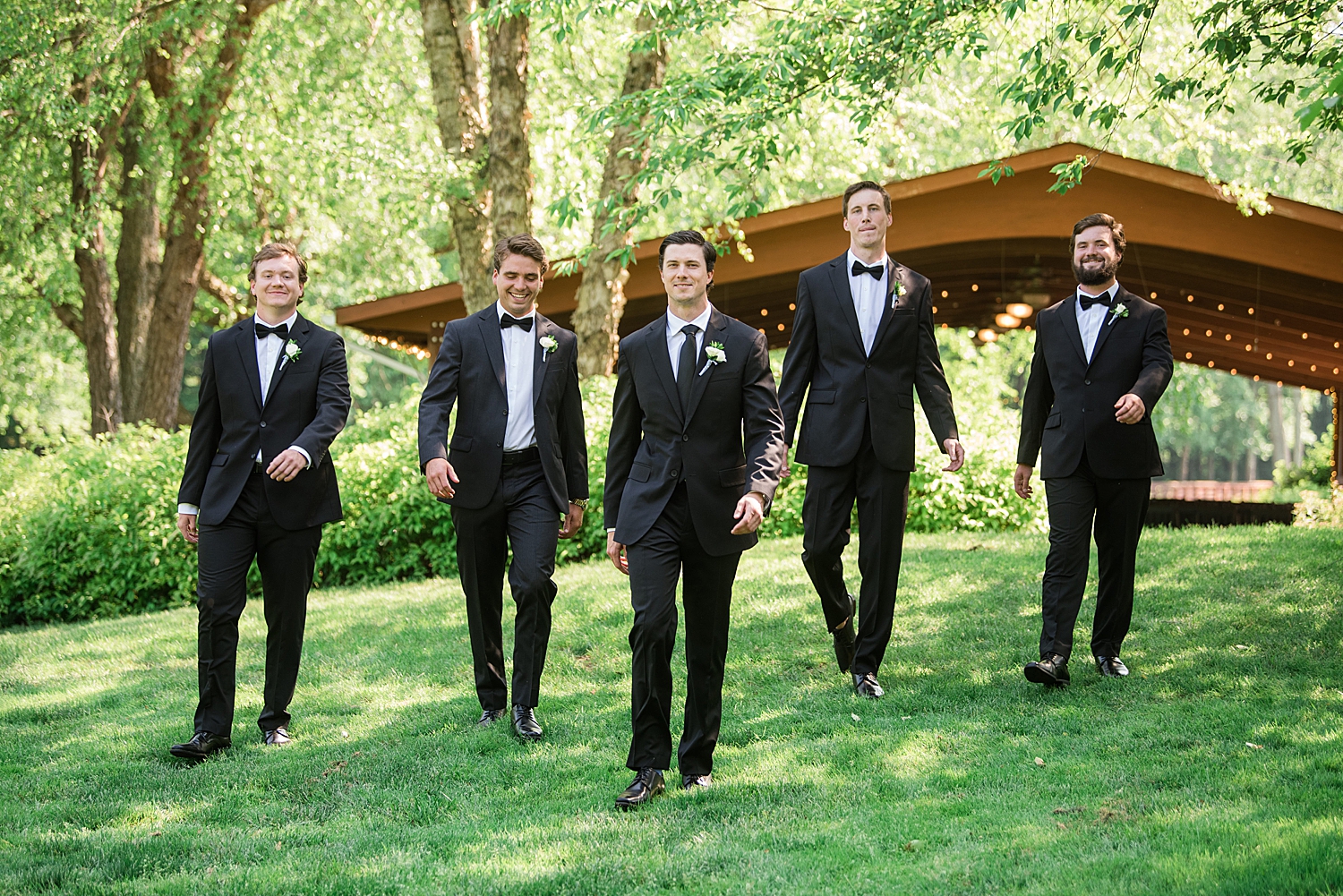 groom and groomsmen walking through trees at gold club