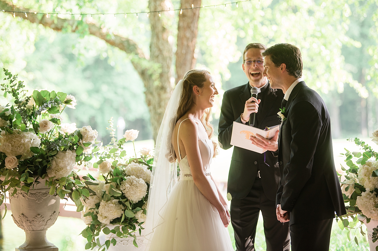 bride and groom laughing with officiant during ceremony