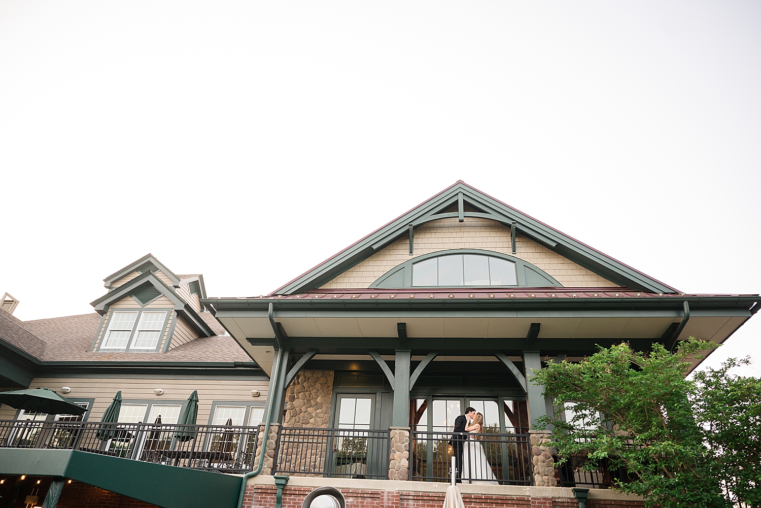 bride and groom kiss on golf club balcony