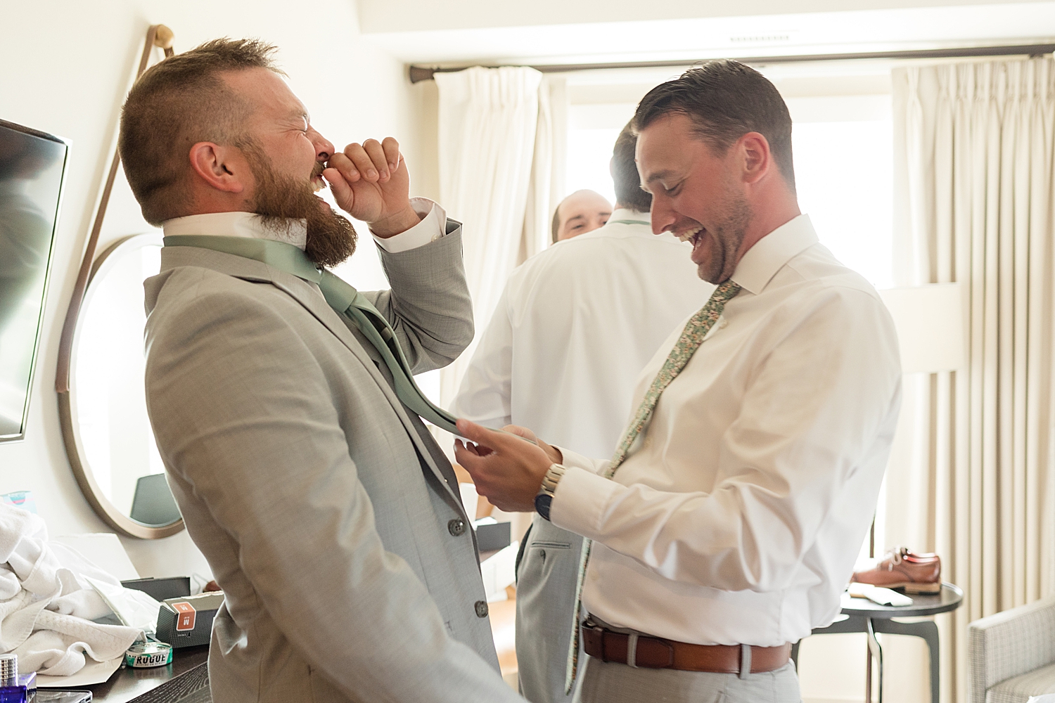 groom getting ready, groomsmen helping with tie