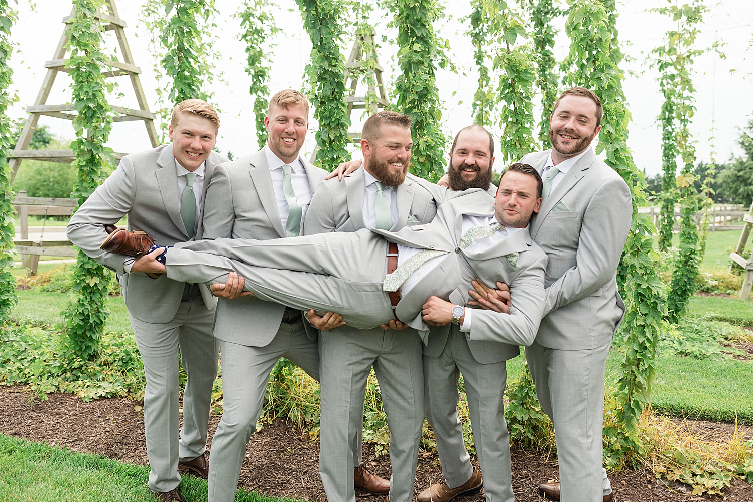 groomsmen holding groom in garden at chesapeake bay beach club inn