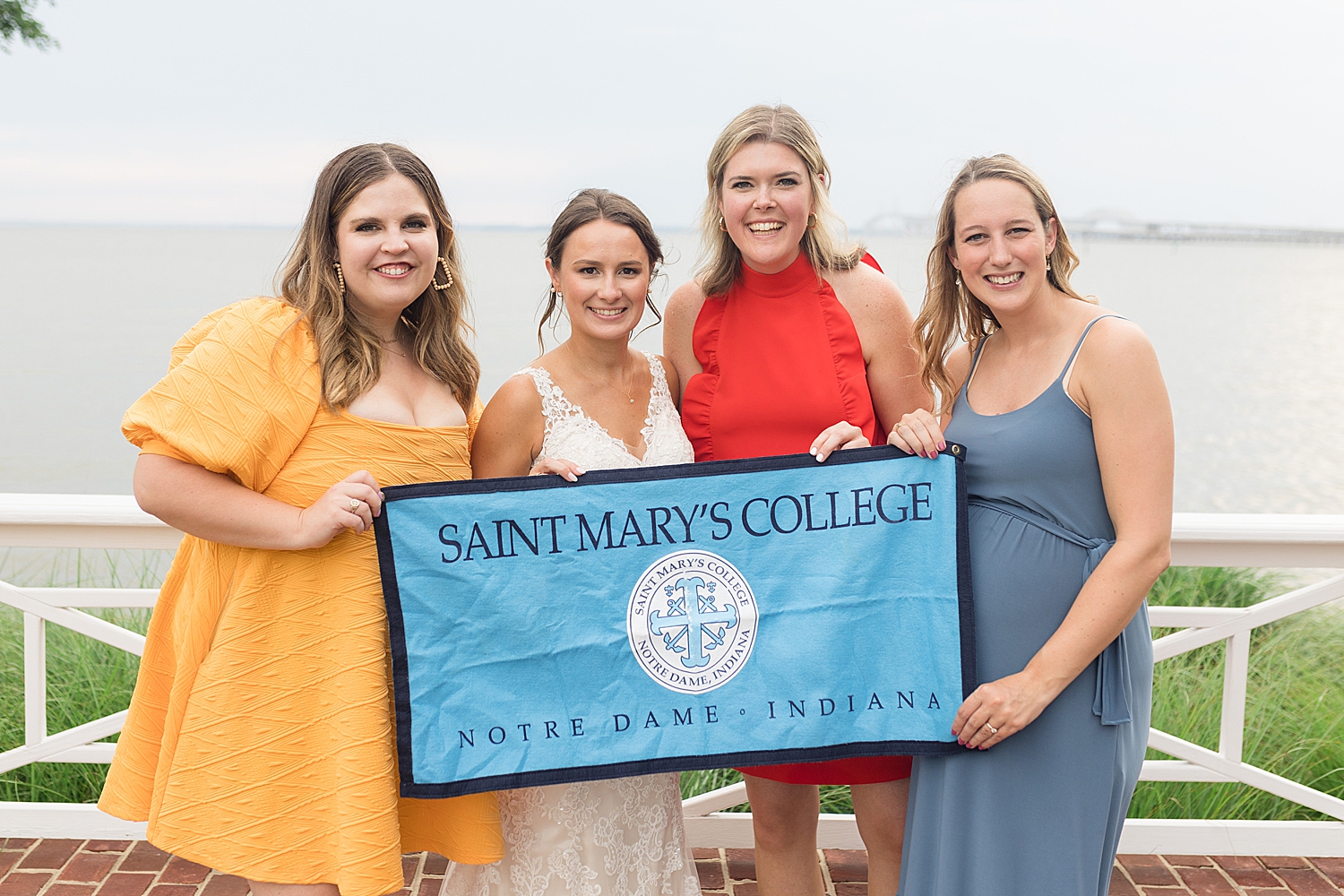 bride and friends hold up saint mary's college banner