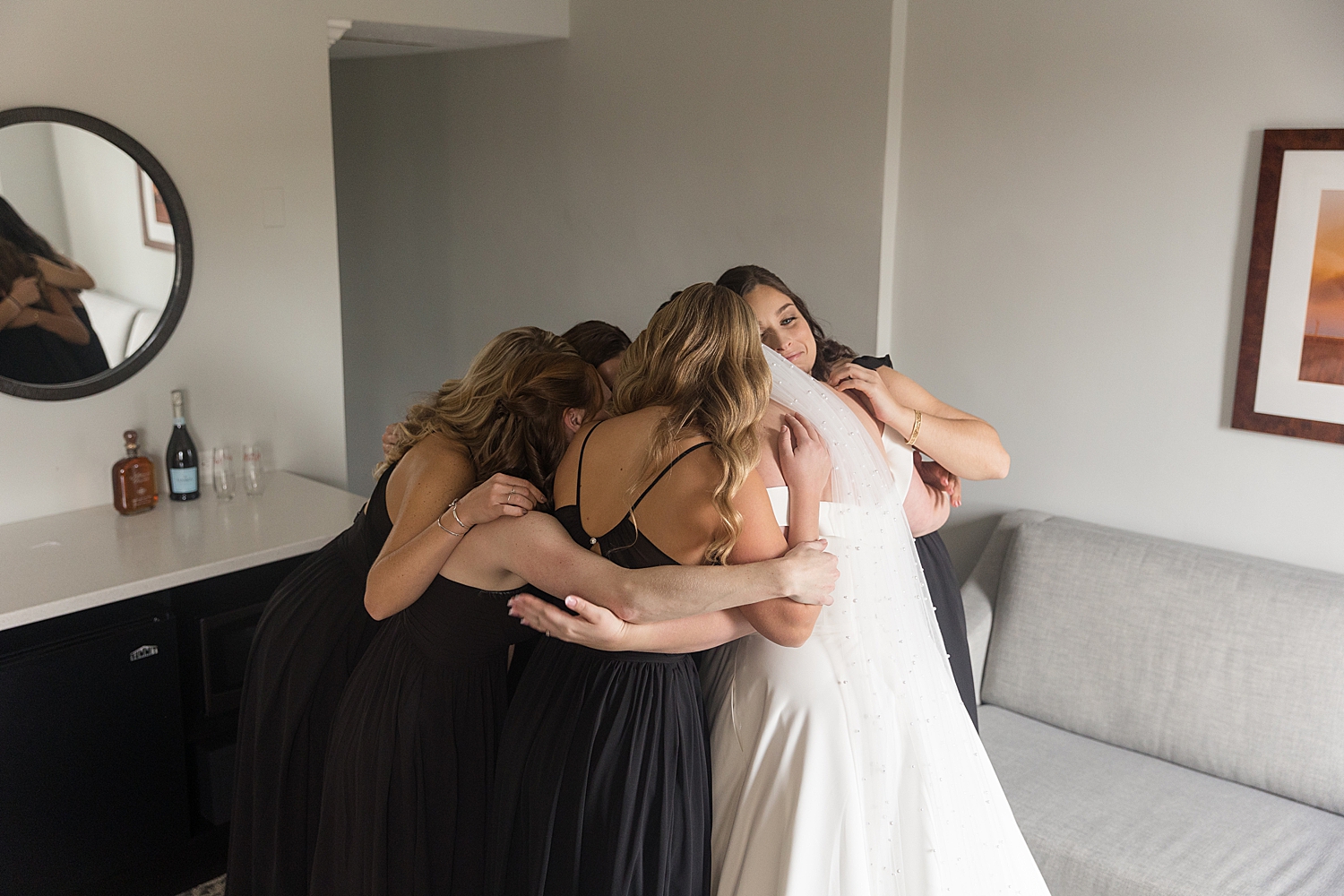 bride and bridesmaids hug in hotel room