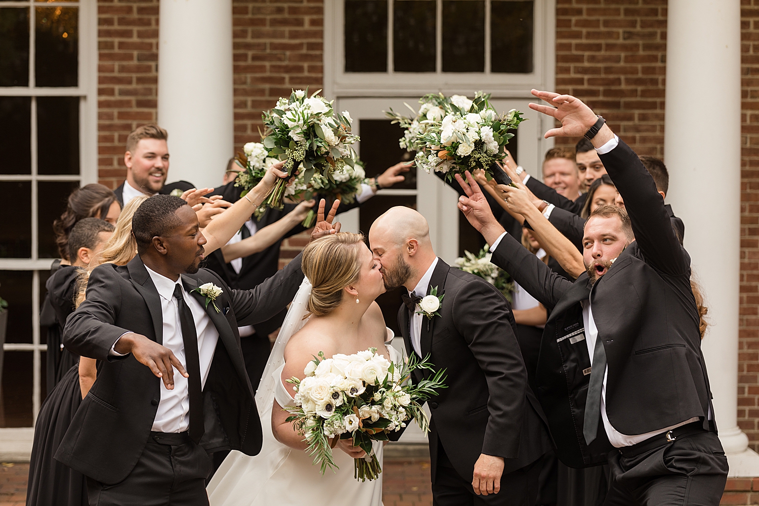 bride and groom kiss while wedding party creates tunnel