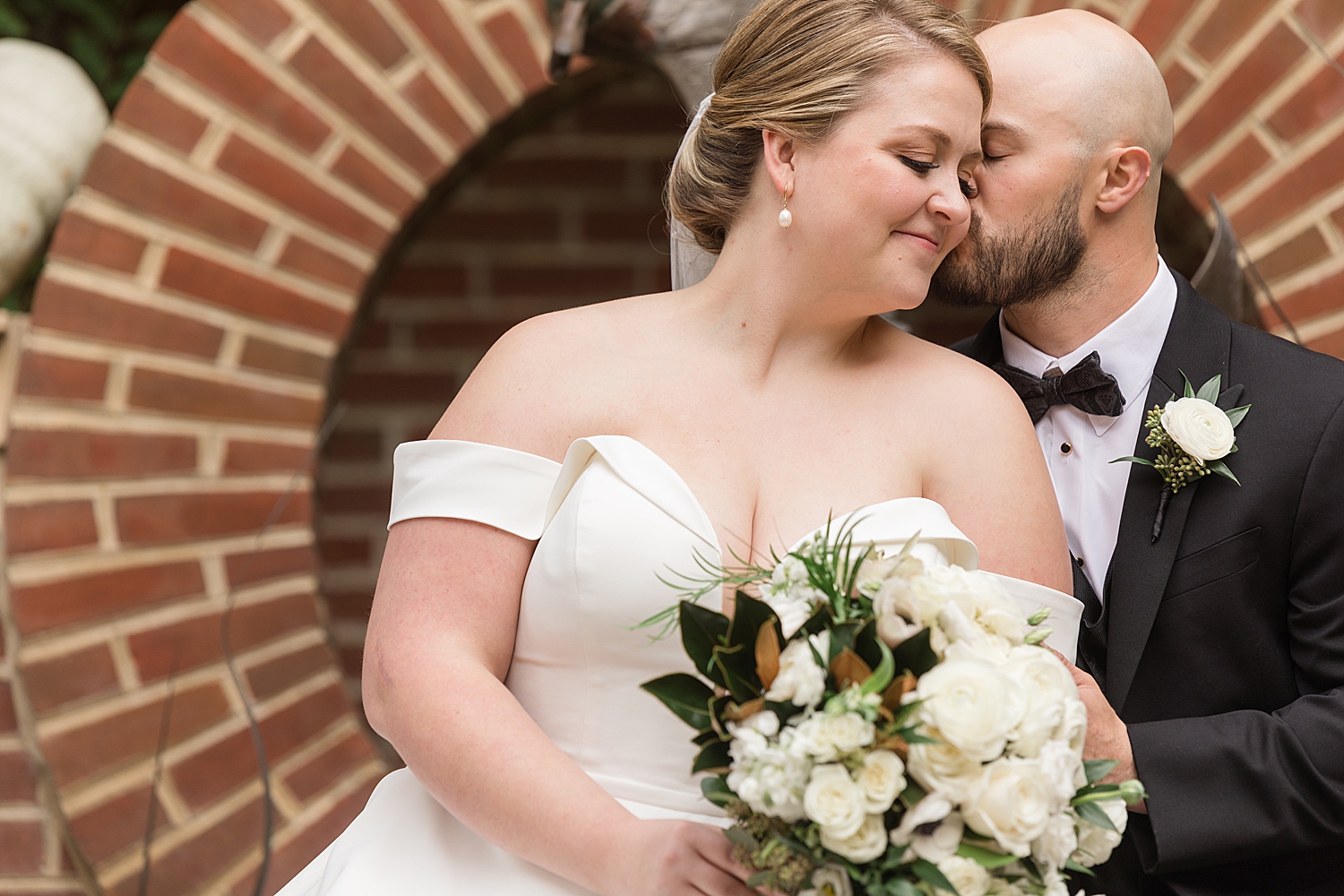 groom kisses bride on cheek