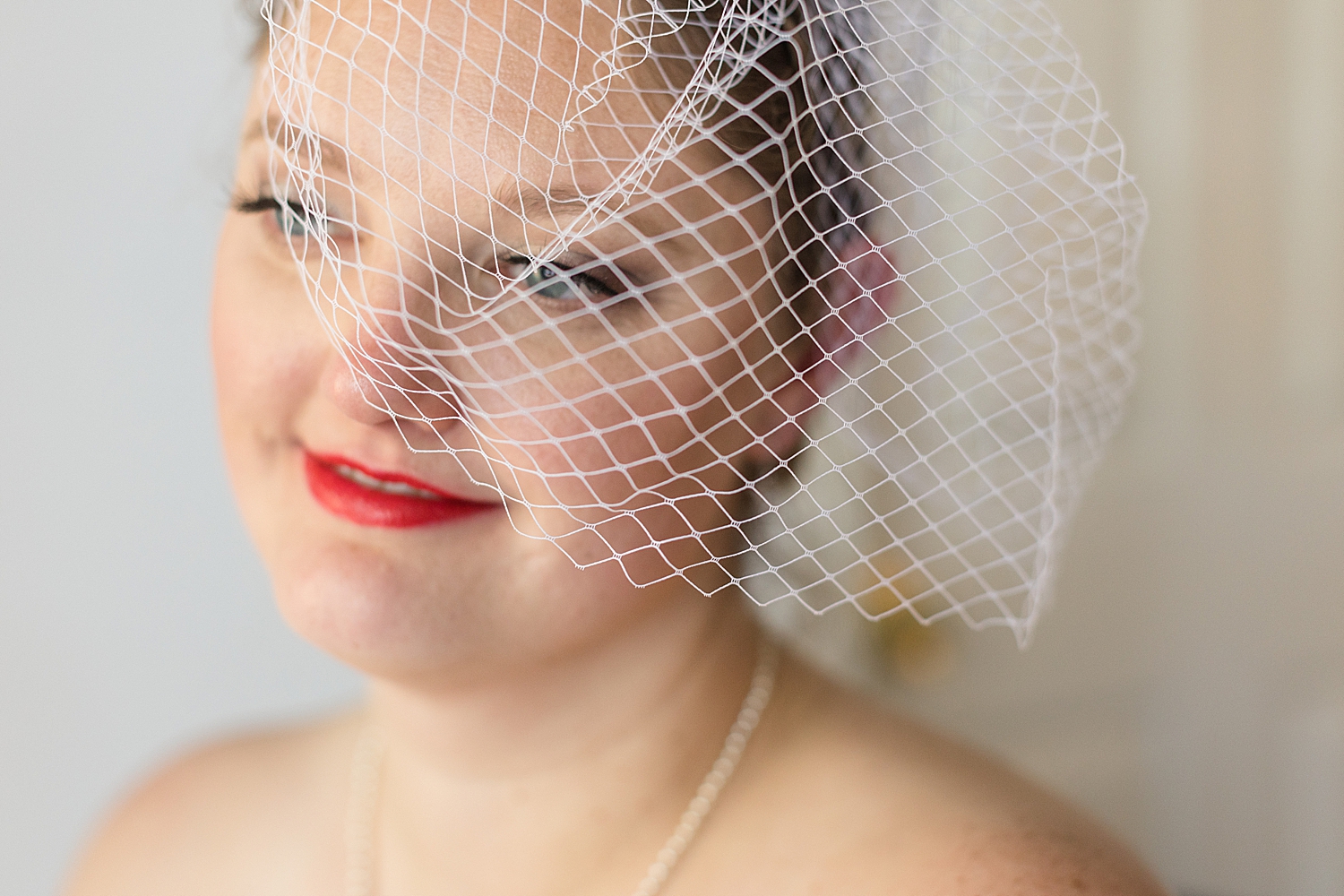 bride portrait wearing white netted fascinator hat