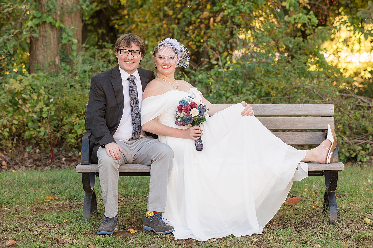 bride and groom portrait wearing white netted fascinator hat on bench