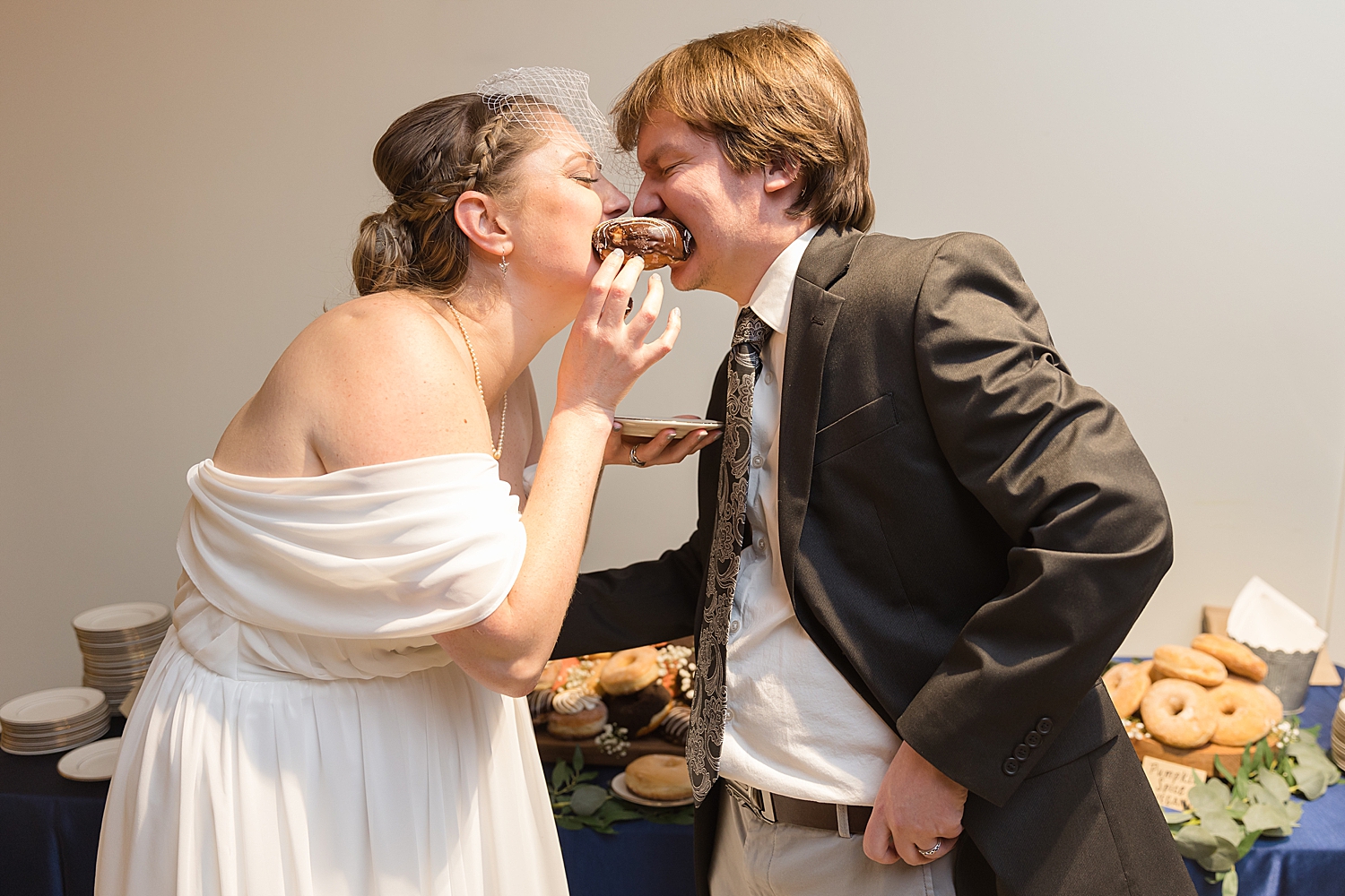 bride and groom bite into donut together