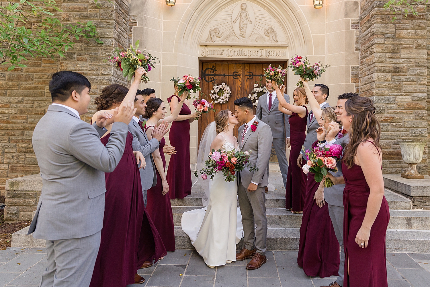 bride and groom kiss under wedding party tunnel